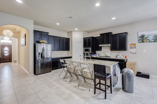 Kitchen with stainless steel appliances, a sink, dark cabinets, arched walkways, and tasteful backsplash | Image 8
