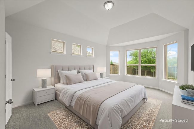 Primary bedroom with a vaulted ceiling and view of the backyard. | Image 14