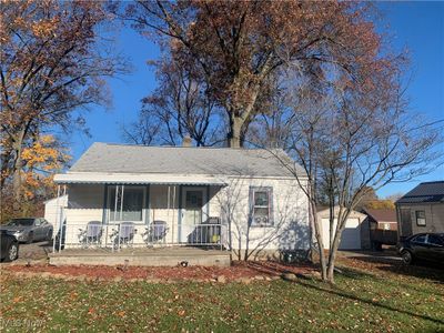 View of front of house with a porch, a front yard, a garage, and a storage shed | Image 1