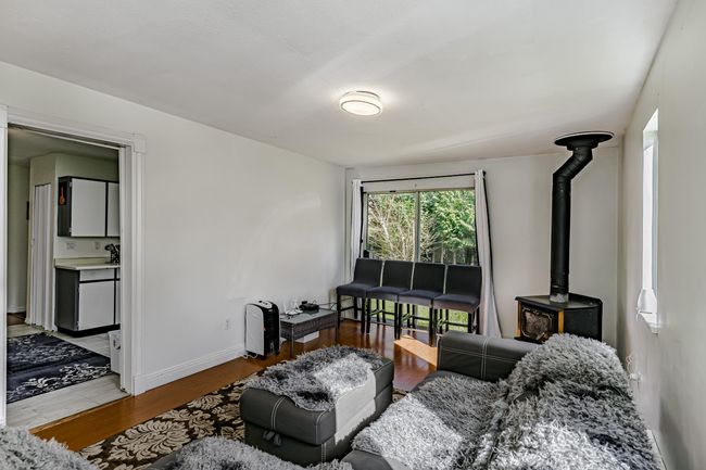 Living room with baseboards, wood finished floors, and a wood stove | Image 4
