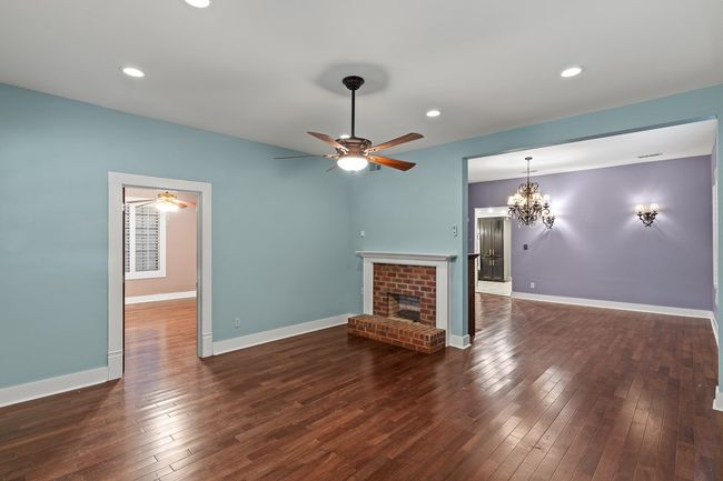 Unfurnished living room featuring a ceiling fan, a brick fireplace, hardwood / wood-style flooring, recessed lighting, and a chandelier | Image 8