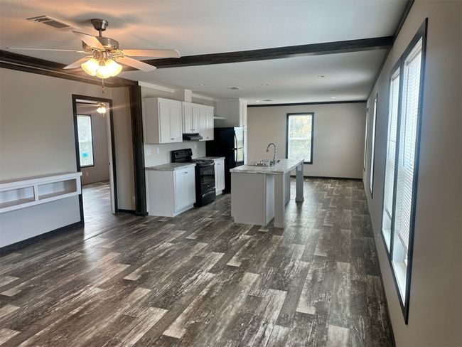 Kitchen with black range with electric cooktop, dark wood finished floors, visible vents, white cabinets, and ceiling fan | Image 4
