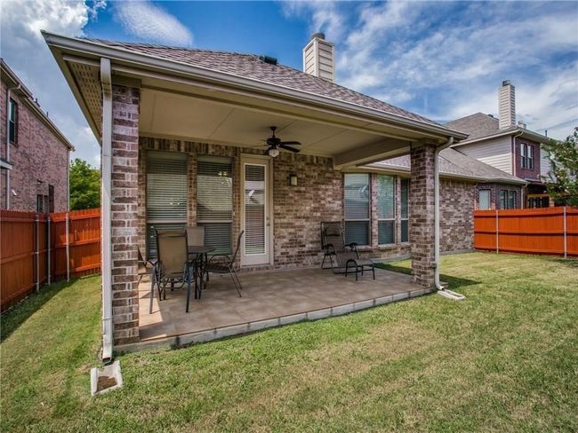 Back of house with ceiling fan, a patio area, a chimney, and brick siding | Image 23