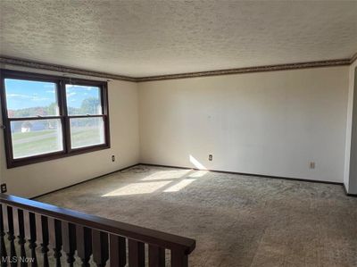 Empty room featuring a textured ceiling, carpet flooring, and crown molding | Image 2