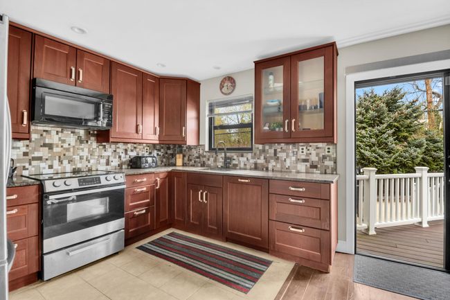 Kitchen with black microwave, light stone countertops, stainless steel electric range oven, and a sink | Image 8