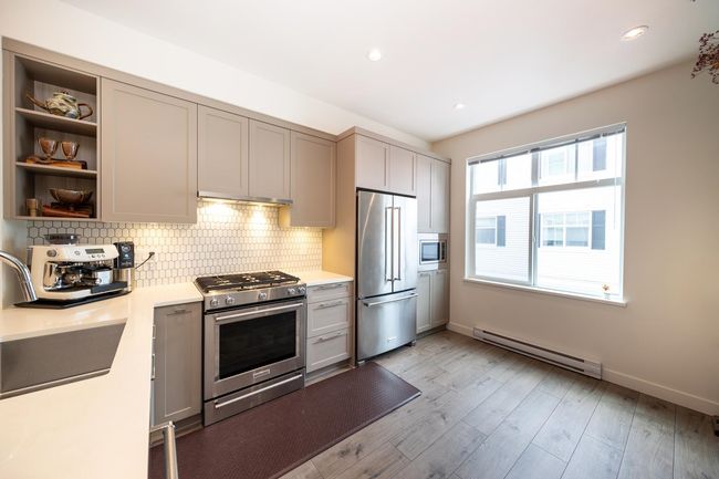 Kitchen featuring stainless steel appliances, a baseboard heating unit, a sink, light countertops, and recessed lighting | Image 9