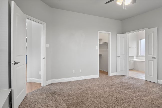 Unfurnished bedroom featuring carpet, a spacious closet, ensuite bath, baseboards, and a closet | Image 25