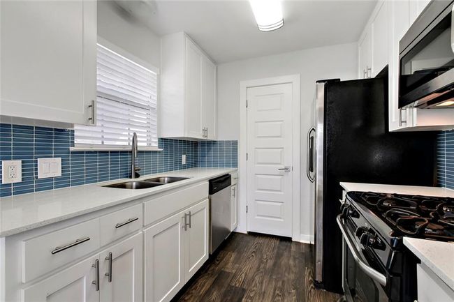 Kitchen with white cabinets, appliances with stainless steel finishes, dark wood-type flooring, and a sink | Image 9