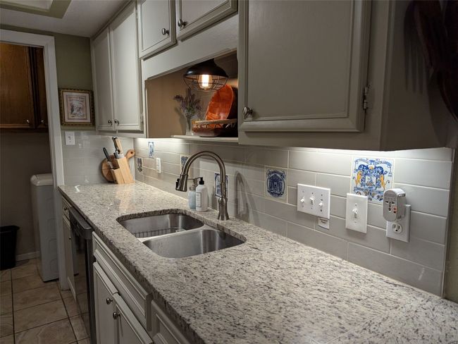 Kitchen featuring backsplash, black dishwasher, light tile patterned floors, and light stone counters | Image 14