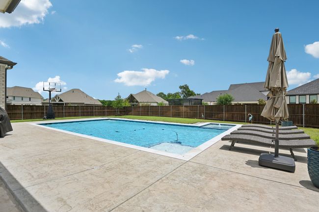 View of swimming pool with a fenced backyard, a patio area, and a residential view | Image 37