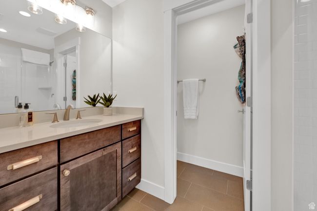 Bathroom featuring vanity, tile patterned floors, a shower, and baseboards | Image 30
