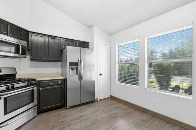 Kitchen with appliances with stainless steel finishes, vaulted ceiling, light countertops, and light wood-type flooring | Image 13