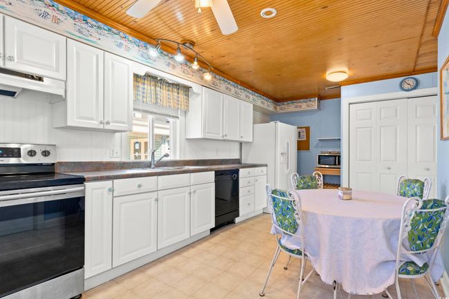 Kitchen featuring stainless steel appliances, ceiling fan, exhaust hood, wooden ceiling, and white cabinetry | Image 13