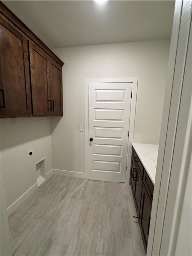 Washroom with hookup for an electric dryer, cabinet space, and light wood-type flooring | Image 42