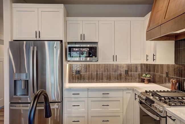 Kitchen with appliances with stainless steel finishes, white cabinetry, premium range hood, and backsplash | Image 8
