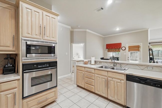Kitchen with visible vents, appliances with stainless steel finishes, a sink, light brown cabinets, and ornamental molding | Image 14