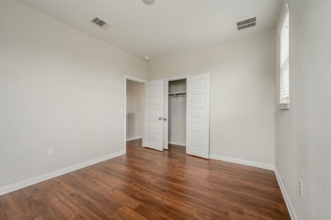 Unfurnished bedroom with baseboards, dark wood-style floors, and visible vents | Image 28