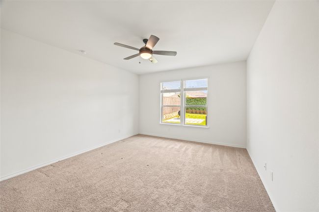 Unfurnished room featuring light colored carpet, a ceiling fan, baseboards, and a smoke detector | Image 17