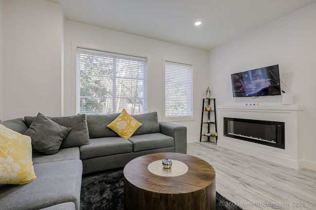 Living area with light wood finished floors, a glass covered fireplace, and recessed lighting | Image 18