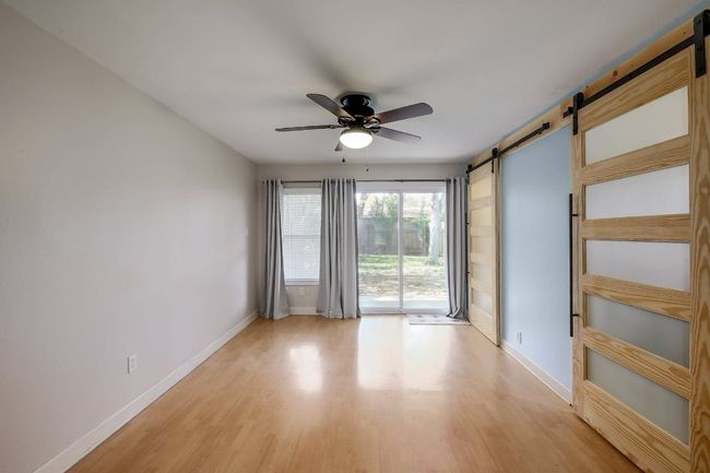 Empty room featuring a barn door, ceiling fan, baseboards, and light wood-type flooring | Image 28