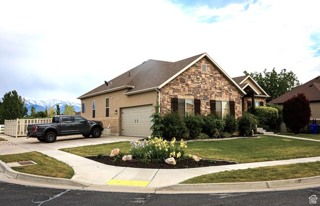 View of front of home with stone siding, a garage, a front yard, concrete driveway, and a mountain view | Image 62