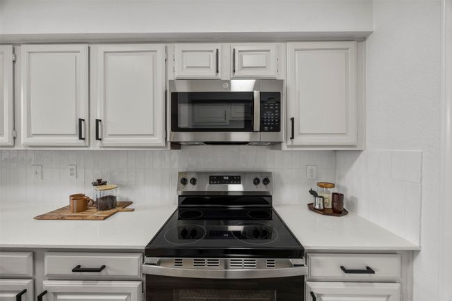Kitchen with appliances with stainless steel finishes, light countertops, backsplash, and white cabinetry | Image 17
