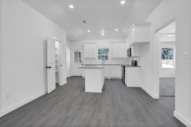 Kitchen with electric range oven, baseboards, recessed lighting, white cabinetry, and a kitchen island | Image 4