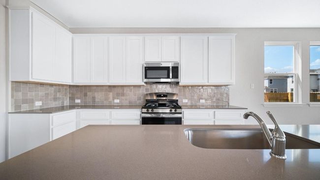 Kitchen with stainless steel appliances, white cabinetry, backsplash, and dark countertops | Image 15