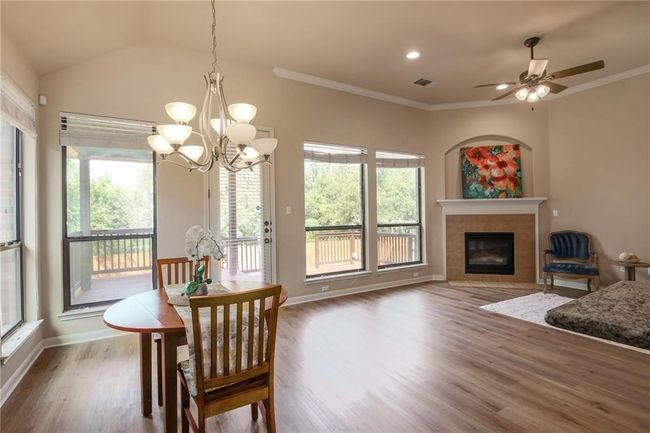 Dining room with healthy amount of natural light, a chandelier, wood finished floors, a tiled fireplace, and ornamental molding | Image 9