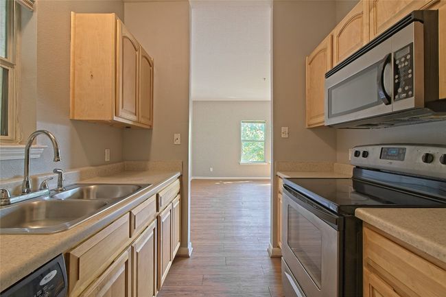 Kitchen featuring stainless steel appliances, light brown cabinets, wood finished floors, and light countertops | Image 20