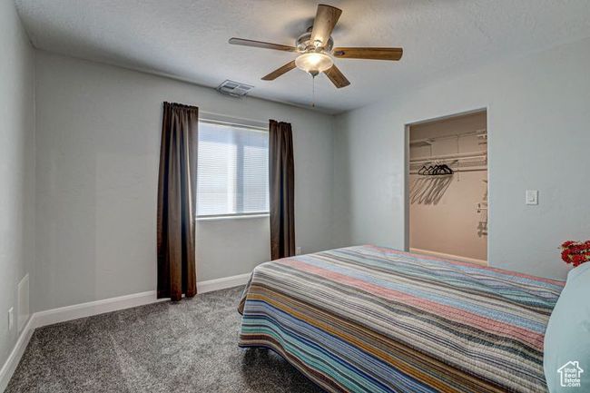 Carpeted bedroom featuring a textured ceiling, visible vents, a ceiling fan, and baseboards | Image 20