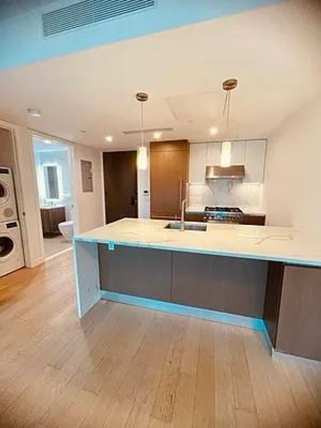 Kitchen with stacked washer and clothes dryer, light wood-style floors, range, a sink, and recessed lighting | Image 16