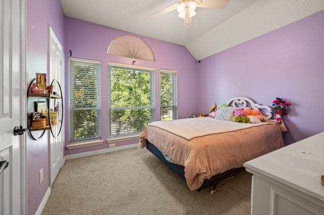 Carpeted bedroom with lofted ceiling, ceiling fan, and a textured ceiling | Image 25