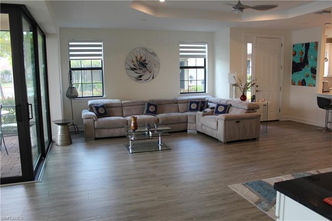 Living room featuring visible vents, baseboards, ceiling fan, dark wood-style floors, and a raised ceiling | Image 6