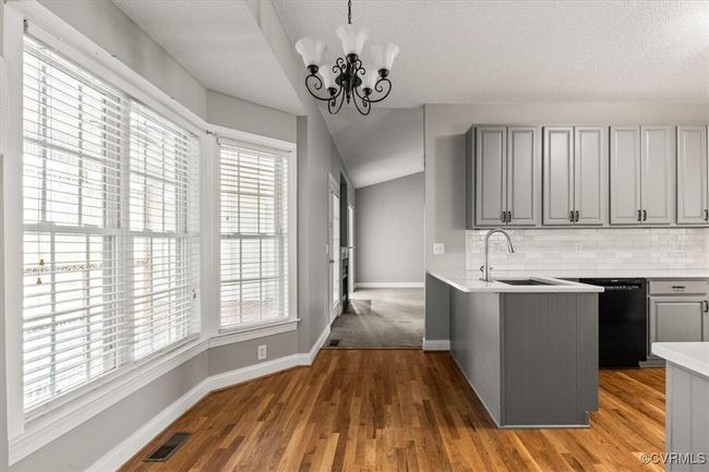 Kitchen with black dishwasher, gray cabinetry, a sink, a peninsula, and light countertops | Image 17