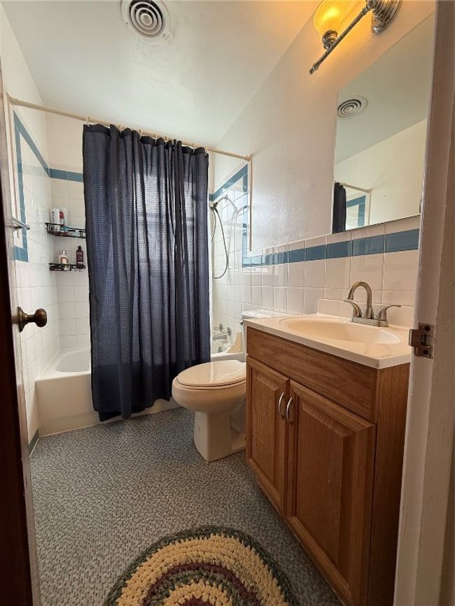 Bathroom with shower / bath combo with shower curtain, tile walls, toilet, and vanity | Image 12