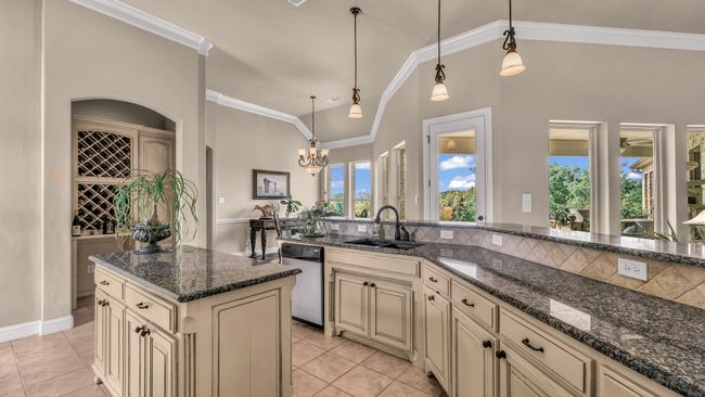 Kitchen featuring light tile patterned flooring, cream cabinetry, a sink, dishwasher, and decorative light fixtures | Image 16