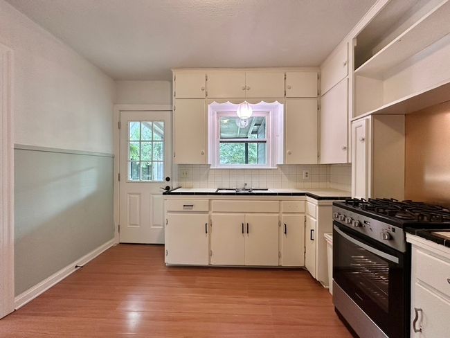 Kitchen with gas range, light wood-style floors, tasteful backsplash, and white cabinetry | Image 21