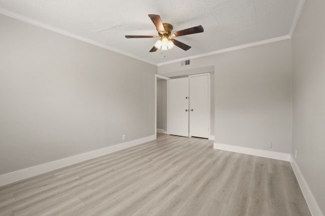 Spare room with light wood-style floors, ceiling fan, a textured ceiling, and ornamental molding | Image 25