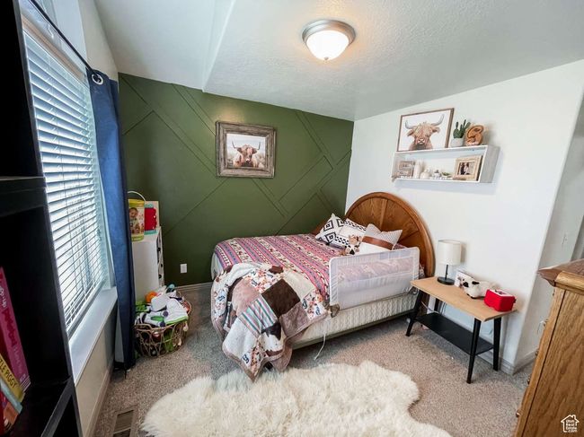Bedroom featuring carpet flooring, a textured ceiling, and baseboards | Image 5