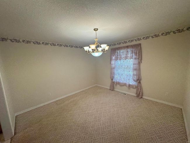 Empty room with carpet floors, an inviting chandelier, and a textured ceiling | Image 14