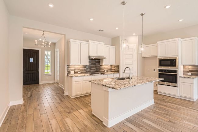 Kitchen featuring under cabinet range hood, light wood-style flooring, a sink, and black appliances | Image 12