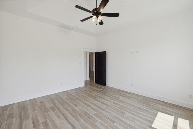 Unfurnished room featuring ceiling fan, light hardwood / wood-style floors, and a tray ceiling | Image 23