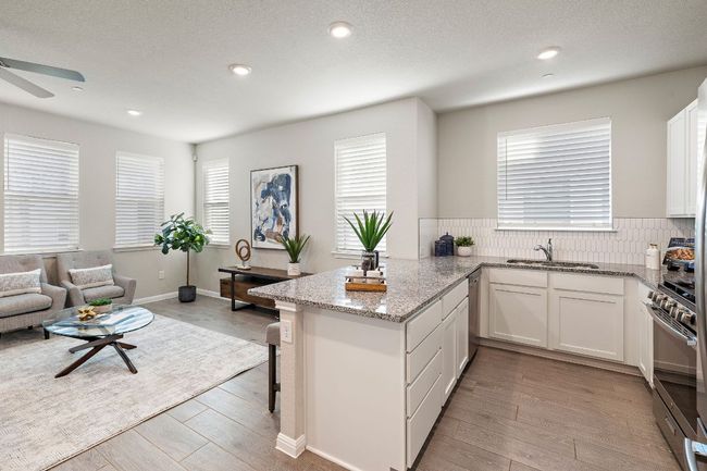 Kitchen with white cabinets, a sink, light wood-type flooring, stainless steel appliances, and light stone counters | Image 12