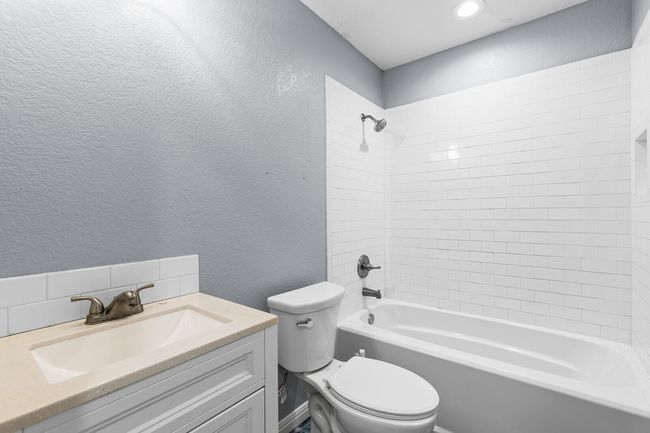 Full bathroom featuring a textured wall, shower combination, and vanity | Image 26