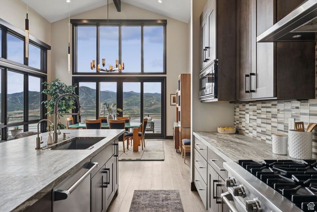 Kitchen with appliances with stainless steel finishes, a mountain view, light wood-type flooring, high vaulted ceiling, and dark brown cabinets | Image 4