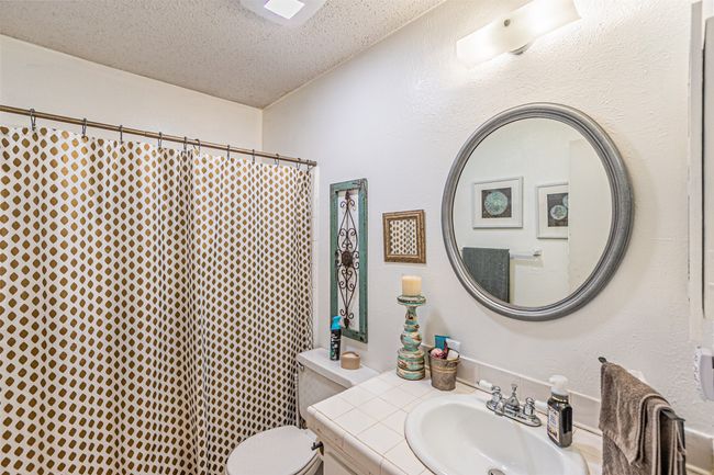 Full bath featuring toilet, vanity, a textured ceiling, and a shower with shower curtain | Image 19