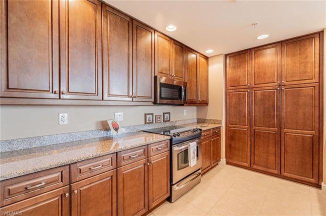 Kitchen with light tile patterned flooring, stainless steel appliances, and light stone countertops | Image 19
