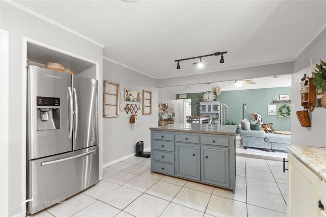 Kitchen with track lighting, open floor plan, stainless steel fridge, a ceiling fan, and light tile patterned floors | Image 12