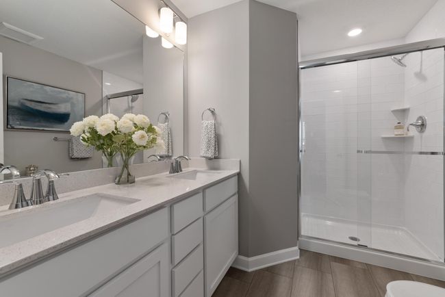 (Photo of decorated model, actual home's finishes will vary) The owner's bathroom offers a double-vanity with quartz countertops, and a walk in shower. | Image 14